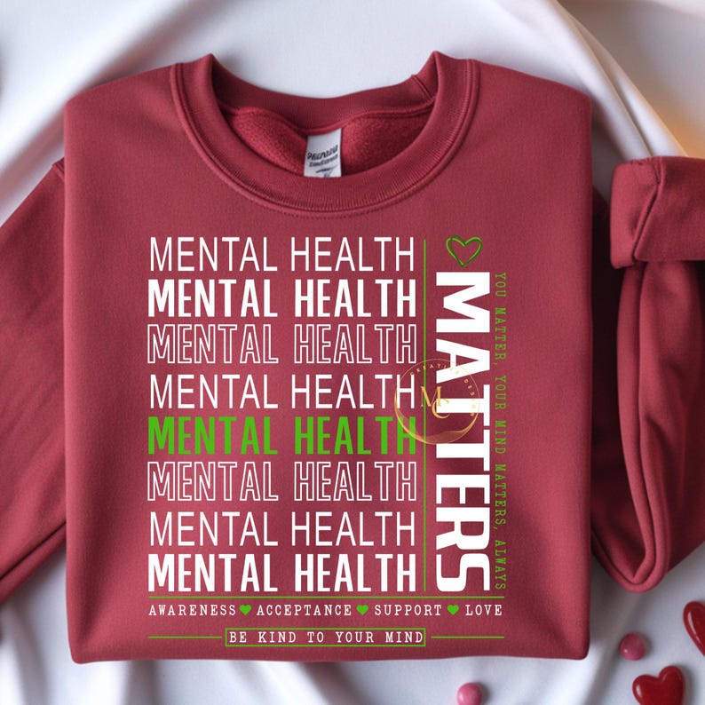 May include: A maroon sweatshirt with the words "MENTAL HEALTH" repeated vertically in white, with one instance in green. The word "MATTERS" is printed vertically in white. The phrases "YOU MATTER, YOUR MIND MATTERS, ALWAYS" and "AWARENESS ACCEPTANCE SUPPORT LOVE" are also printed on the sweatshirt.