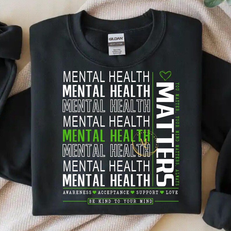 May include: Black sweatshirt with the words "MENTAL HEALTH" stacked vertically in white, with some lines in green. The word "MATTERS" is printed vertically in white with a green heart. The text "YOU MATTER, YOUR MIND MATTERS, ALWAYS" is printed vertically in green. The text "BE KIND TO YOUR MIND" is printed at the bottom.