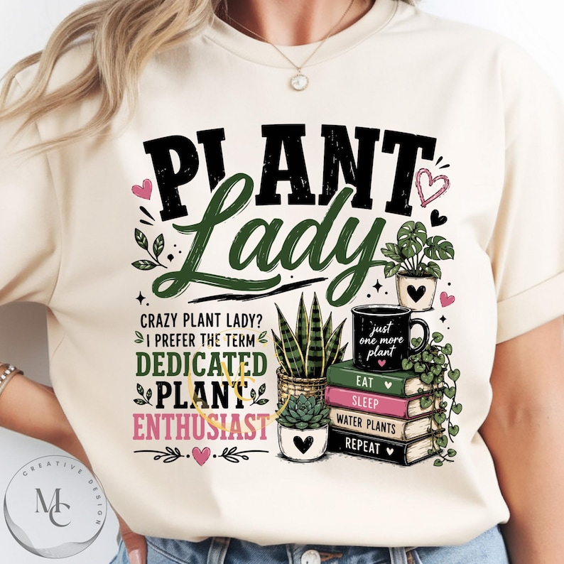 May include: A cream-colored t-shirt featuring a graphic print with the text "PLANT LADY" in black and green, "CRAZY PLANT LADY? I PREFER THE TERM DEDICATED PLANT ENTHUSIAST" in black, green, and pink, and a stack of books labeled "EAT SLEEP WATER PLANTS REPEAT."