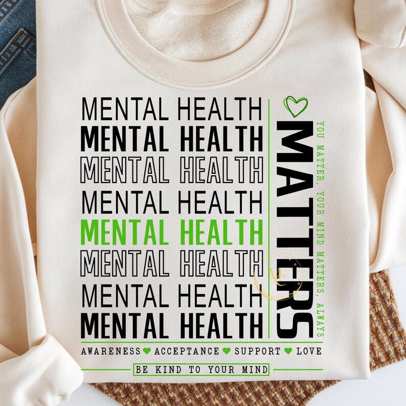 May include: Cream-colored sweatshirt with the words "MENTAL HEALTH" stacked vertically in black and green. The word "MATTERS" is printed vertically in green with the phrase "YOU MATTER, YOUR MIND MATTERS, ALWAYS". The bottom reads "BE KIND TO YOUR MIND".