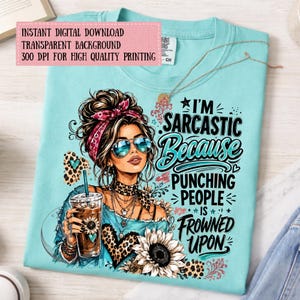 Pode incluir: Uma t-shirt azul-clara com o gr&aacute;fico de uma pessoa com um coque desarrumado, uma fita vermelha com padr&atilde;o e &oacute;culos de sol, segurando um caf&eacute;. O texto diz: I'M SARCASTIC BECAUSE PUNCHING PEOPLE IS FROWNED UPON. Inclui detalhes de leopardo.