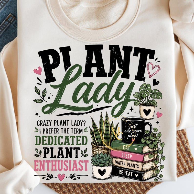 May include: A cream-colored sweatshirt featuring the text "PLANT LADY" in black and green, with additional text "CRAZY PLANT LADY? I PREFER THE TERM DEDICATED PLANT ENTHUSIAST". Graphics include potted plants, a mug, and a stack of books.
