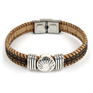 May include: A brown and tan bracelet with a silver clasp and decorative accents. The bracelet features a central silver seashell design and is made of cork and leather. The clasp is marked "STAINLESS STEEL".