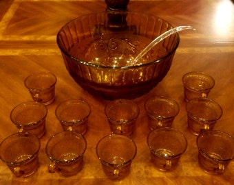 May include: A set of amber glass punch bowl and cups. The punch bowl has a fluted design and a ladle. The cups have a textured design.