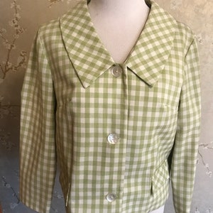 May include: A green and white gingham blazer with a large collar and three buttons. The blazer has a pocket on the left side.