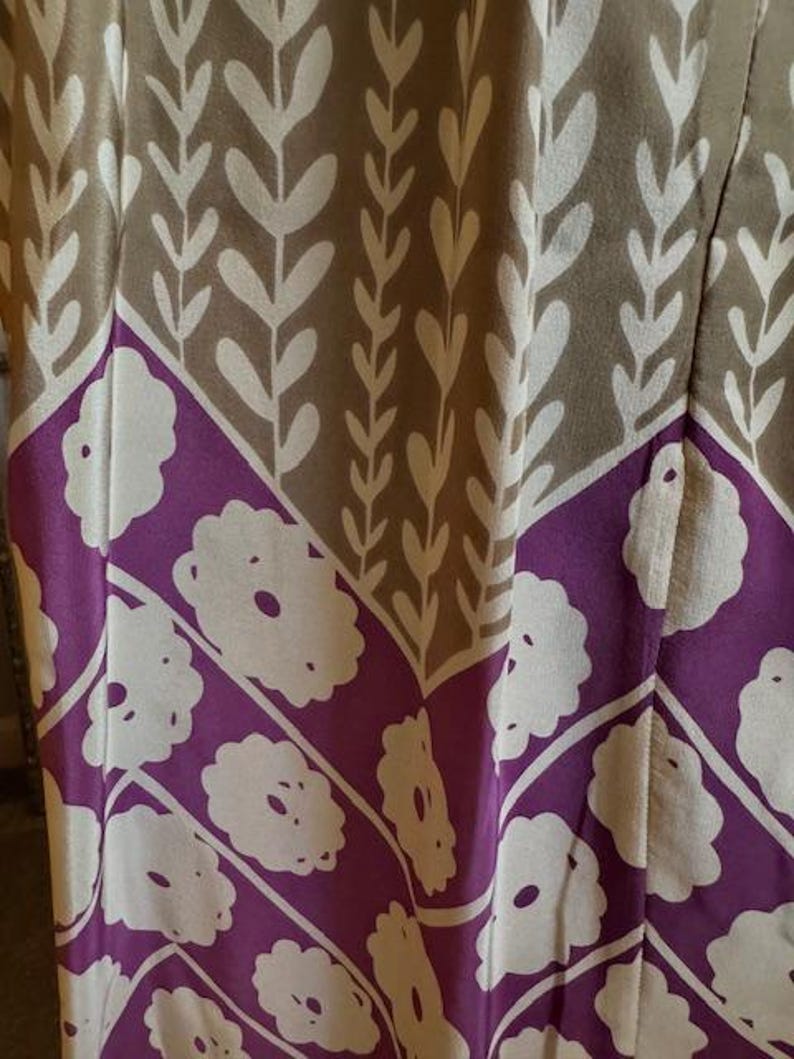 Puede incluir: Primer plano de una tela estampada, probablemente para ropa. El dise&ntilde;o se divide en secciones beige y moradas. Las secciones beige tienen un patr&oacute;n de hojas blancas, y las secciones moradas tienen un dise&ntilde;o floral blanco. La tela es probablemente para un vestido o prenda similar.