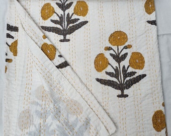 May include: White kantha quilt with a floral pattern in yellow and black. The quilt is folded in half and has a hand-stitched design.