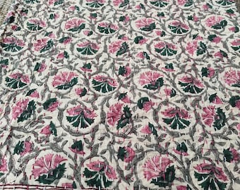 May include: A floral patterned quilt featuring pink and green flowers on a cream background. The quilt has a decorative border with a repeating design in a deep burgundy color. The stitching is visible throughout the quilt.