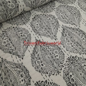 May include: White cotton fabric with a black paisley print. The fabric is rolled up and the print is visible on the surface.