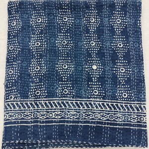 Pode incluir: Uma colcha kantha azul e branca com um padr&atilde;o geom&eacute;trico. A colcha tem uma borda com um desenho repetitivo.