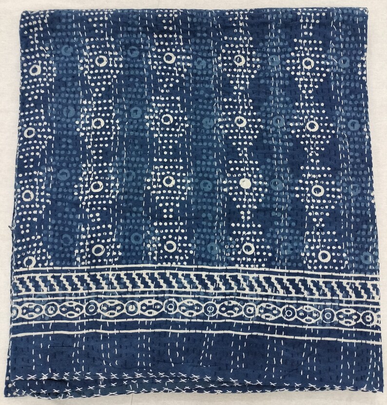 Pode incluir: Uma colcha kantha azul e branca com um padr&atilde;o geom&eacute;trico. A colcha tem uma borda com um desenho repetitivo.