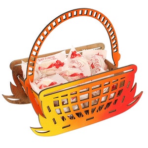May include: Orange and yellow wooden basket with a handle, filled with small white candies wrapped in red and white paper. The candy wrappers have the text "Raffaello" printed on them.