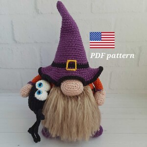 May include: A handmade crochet gnome wearing a purple witch's hat with a black band and gold buckle. The gnome has a long, beige beard and is holding a black spider with blue eyes. The text "PDF pattern" is visible.