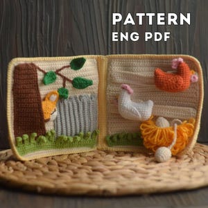 Puede incluir: Un libro infantil de ganchillo con temática de granja. El libro presenta un zorro, un árbol, una valla, dos gallinas y un nido con huevos. El texto "PATTERN ENG PDF" se muestra en la parte superior. El libro está abierto sobre una estera tejida.