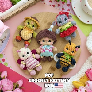 May include: Five small crocheted dolls featuring a turtle, a bear with brown hair, a grey animal with a red skirt, a pink and white butterfly, and a yellow and black bee. The text PDF CROCHET PATTERN ENG with a US flag is visible.