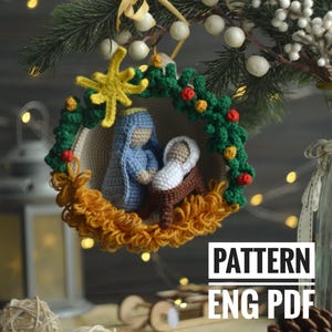 Op de afbeelding: Gehaakt kerst ornament met een kerststal met Maria, Jozef en baby Jezus. De ornament is versierd met een gele ster, groene bladeren en rode bessen. De tekst "PATTERN ENG PDF" is zichtbaar onder de ornament.