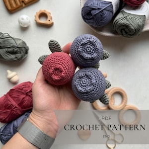 May include: Crochet pattern PDF for making a set of two crocheted berries, one red and one purple, with green leaves. The pattern is in English.