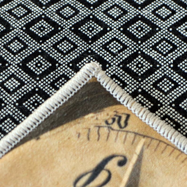 May include: A corner of a beige, circular patch with a white stitched border, featuring a partial view of a black and white patterned fabric. The patch has a vintage aesthetic, with visible text and the number "50".