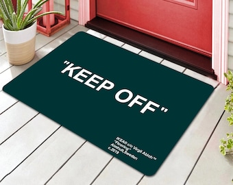May include: A dark green doormat with the text "KEEP OFF" in white lettering. The doormat also includes the text "IKEA® c/o Virgil Abloh™" in white lettering.