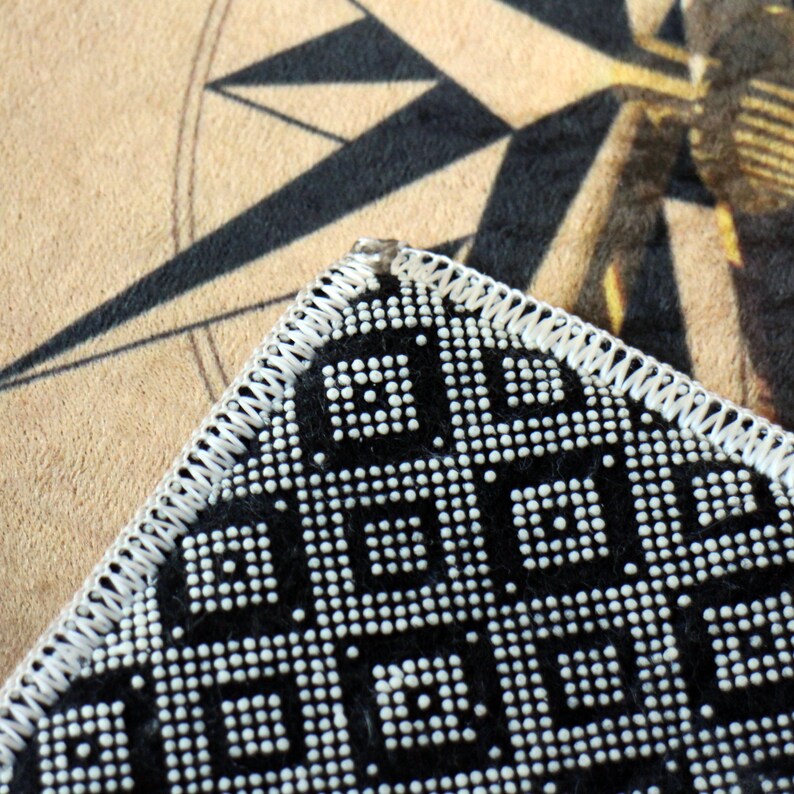 May include: Close-up of a black and white patterned fabric with a white stitched border. The fabric has a geometric design with small white dots.