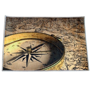 May include: A vintage compass with a gold-colored metal casing and a black needle pointing north. The compass is set against a background of an old, faded map.