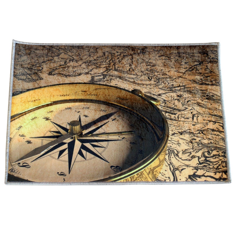 May include: A rectangular rug featuring a vintage compass with a gold-colored bezel and a black and white compass rose. The compass is set against a backdrop of an antique map in shades of brown and beige.