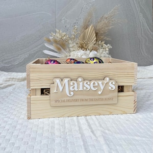 May include: A wooden crate with a personalised sign that says "Maisey's Special Delivery from the Easter Bunny". The crate is filled with colourful foil-wrapped chocolate Easter eggs.