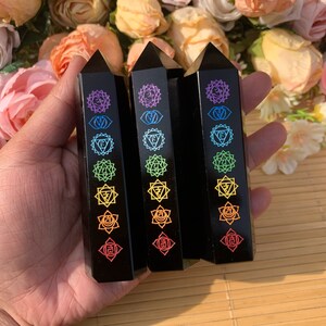Pode incluir: Três varinhas de chakra de obsidiana preta com símbolos de chakra de arco-íris gravados em cada varinha.