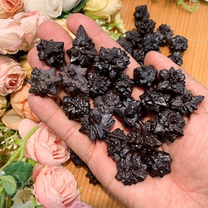 May include: A collection of black, naturally formed, crystal clusters. The crystals are sharp and have a rough, textured surface.