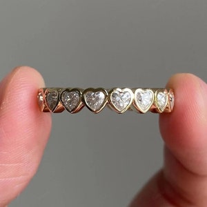 K&ouml;nnte beinhalten: Ein Goldring mit einer Reihe herzf&ouml;rmiger Diamanten.