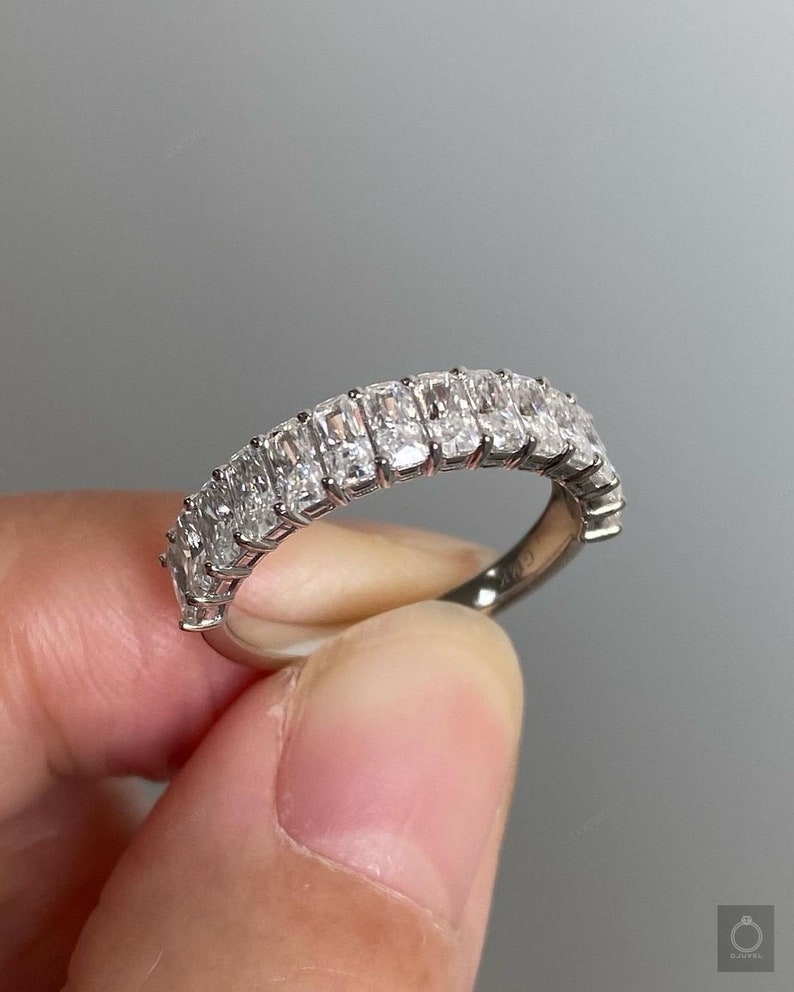 May include: A silver band ring with a row of rectangular-shaped diamonds set in a pave setting.