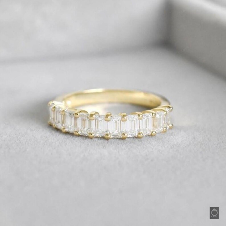 May include: A gold band ring with a row of emerald-cut diamonds.