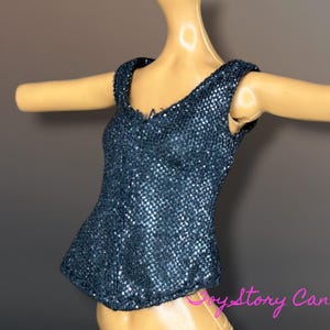 Puede incluir: Un top azul oscuro con lentejuelas y escote en V. El top sin mangas tiene una silueta ajustada y se muestra en un maniqu&iacute;. Las lentejuelas crean un efecto brillante, reflejando la luz. El top est&aacute; dise&ntilde;ado para una mu&ntilde;eca.