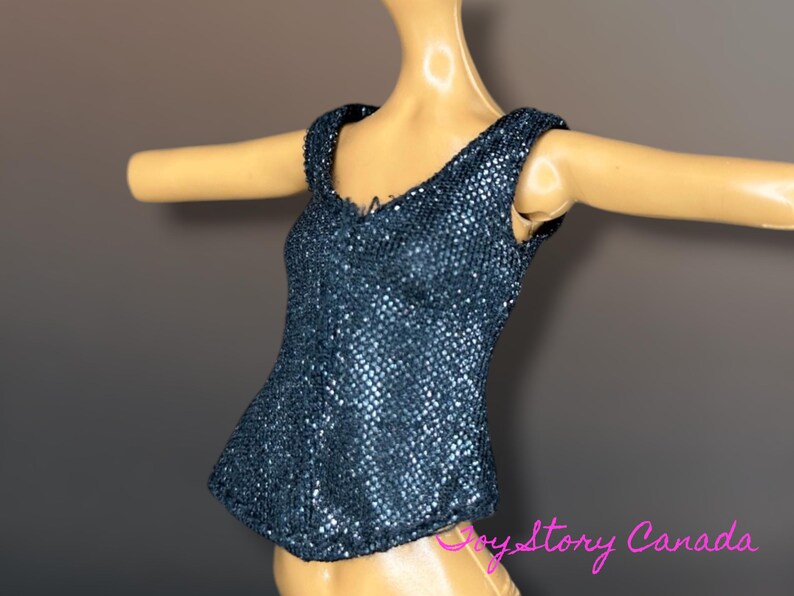 Puede incluir: Un top azul oscuro con lentejuelas y escote en V. El top sin mangas tiene una silueta ajustada y se muestra en un maniqu&iacute;. Las lentejuelas crean un efecto brillante, reflejando la luz. El top est&aacute; dise&ntilde;ado para una mu&ntilde;eca.