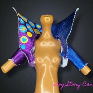 Op de afbeelding: Een poppenjasje met een levendig design. De jas heeft een paarse mouw met een patroon van harten, cirkels en bliksemschichten. De andere mouw is blauw. De jas wordt op een mannequin gepresenteerd.