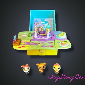 May include: A colorful, open toy playset with a swing, slide, and other features. Three small animal figurines are in front of the playset. The playset is primarily yellow, purple, and teal, with a dark background.