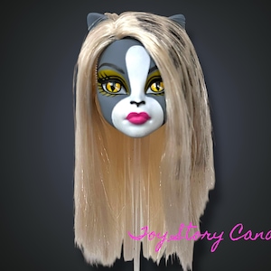 Puede incluir: Una cabeza de muñeca con una cara gris y blanca, ojos amarillos y labios rosados. La muñeca tiene pelo largo y rubio claro y pequeñas orejas de gato grises. La cabeza está montada sobre un soporte transparente sobre un fondo gris oscuro.