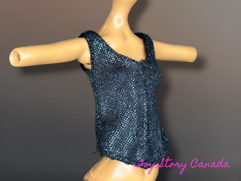 Puede incluir: Una blusa sin mangas azul oscuro con un patr&oacute;n texturizado en forma de escamas. La blusa tiene un escote en V y se muestra en una mu&ntilde;eca. La blusa est&aacute; dise&ntilde;ada para adaptarse a una mu&ntilde;eca.