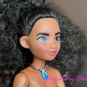 May include: A doll with dark skin, brown eyes, and black curly hair. The doll is wearing a necklace with a blue pendant. The doll's lips are pink, and it has a neutral expression. The doll is a character from a popular animated movie.