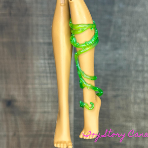 Peut inclure: Une paire de jambes de poupée avec un accessoire en forme de vigne vert translucide enroulé autour d'une jambe.