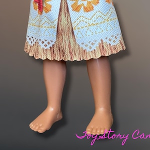 May include: A doll's legs and lower torso are visible, with a patterned skirt in shades of white, orange, and brown. The skirt has a scalloped edge. The doll's skin is a light tan color. The image is set against a gradient background.
