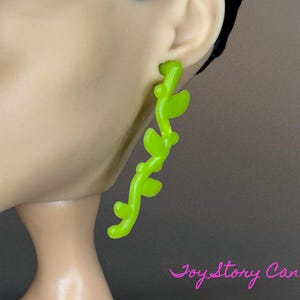 Peut inclure: Une paire de boucles d'oreilles vert néon en forme de vigne avec des feuilles. Les boucles d'oreilles sont en plastique et mesurent environ 5 cm de long.