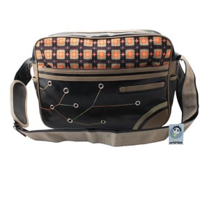 May include: A black messenger bag with a brown and orange geometric pattern on the flap. The bag has a brown strap and a small Superfreak logo tag.