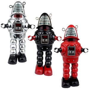 Może przedstawiać: Trzy retro zabawki robotów w kolorze srebrnym, czarnym i czerwonym. Każdy robot ma kopulastą głowę z poziomymi liniami, prostokątny panel na klatce piersiowej i przegubowe ramiona. Roboty stoją na zaokrąglonych nogach i mają czarne stopy.