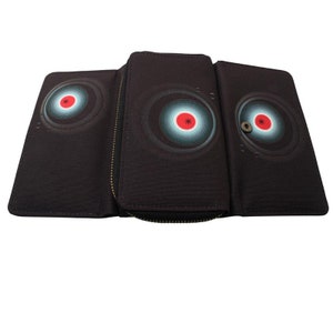 May include: A black trifold wallet with a zipper closure. The wallet features a geometric design with concentric circles in shades of blue, red and white.