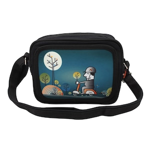 May include: Black canvas shoulder bag with a zip closure. The front of the bag features a colourful illustration of a person riding a scooter in a nighttime forest scene.