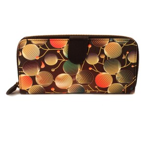 May include: A brown zippered wallet with a colourful abstract pattern of circles and lines. The wallet has a brown flap with a zipper closure.