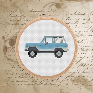 May include: A cross-stitch embroidery in a wooden hoop features a light blue pixelated SUV. The vehicle has black wheels and a white roof. The background is a vintage paper with handwritten script and coffee stains.
