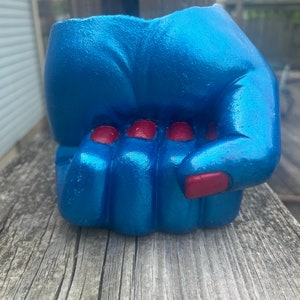 May include: A blue ceramic planter shaped like a fist with red fingernails.