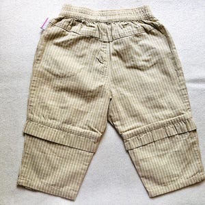 K&ouml;nnte beinhalten: Beige gestreifte Hose mit umgeschlagenem Saum. Die Hose hat einen Kordelzugbund und ist aus einem leichten Stoff gefertigt.